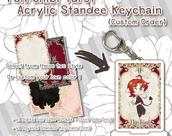 May include: A custom order acrylic keychain featuring a chibi tarot card design. The card is red and gold with a white background and depicts a cartoon character with red hair and a black outfit. The text "The Fool" is printed on the card. The keychain is 7 cm in size and includes two-sided printing.