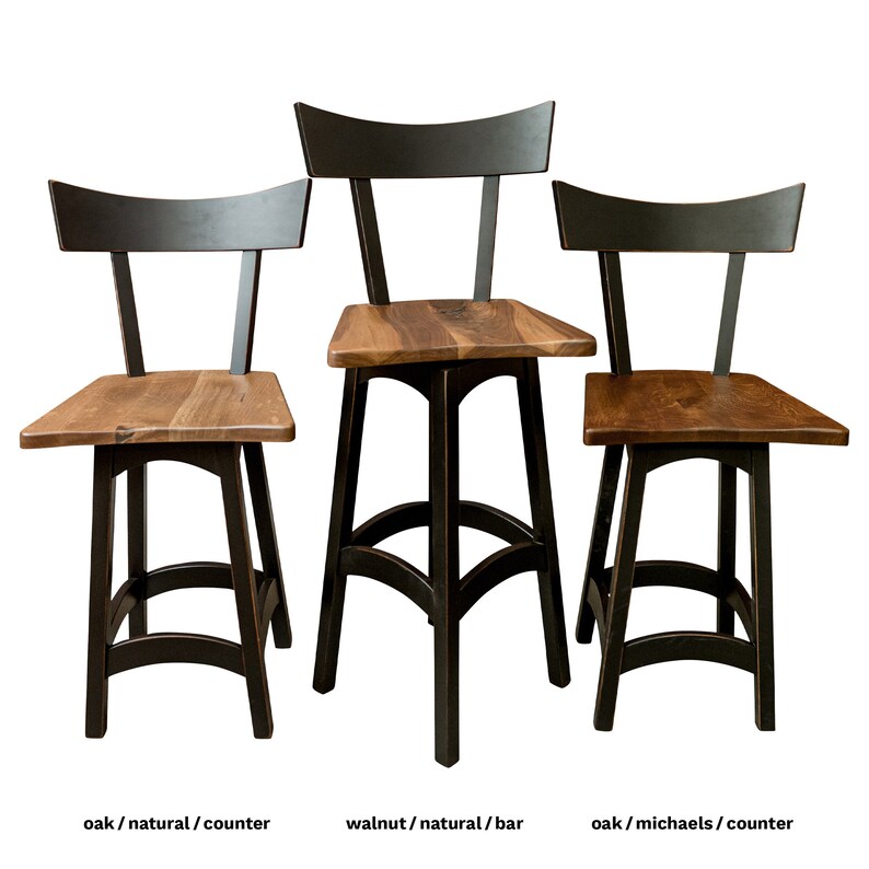 May include: Three wooden bar stools with black metal frames. The stools have a curved back and a wide, flat seat. The stools are made of oak and walnut wood. The stools are shown in three different finishes: natural, natural, and Michaels.