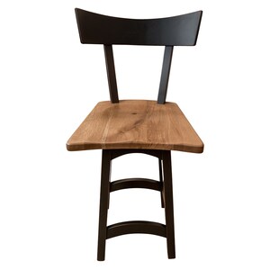 May include: A black and brown wooden bar stool with a curved back and a wide, flat seat. The stool has a simple, modern design.