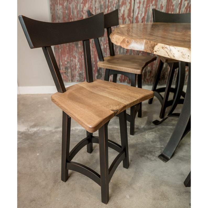 May include: Black and natural wood bar stools with a curved back and a simple design. The stools have a black metal base with a curved design.