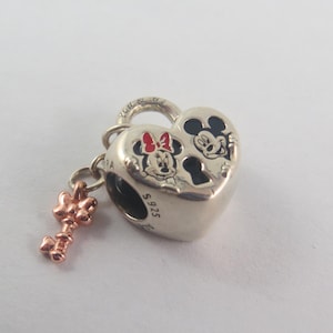 May include: A silver heart-shaped charm with Mickey and Minnie Mouse illustrations. The charm has a key pendant and is marked with "S925". The Mickey and Minnie illustrations are black and red.