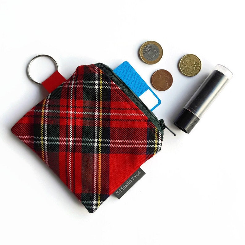 May include: Red and green plaid zippered pouch with a key ring and the text "JESSIESTYLE" on the bottom. The pouch is open and a blue card and coins are visible inside.