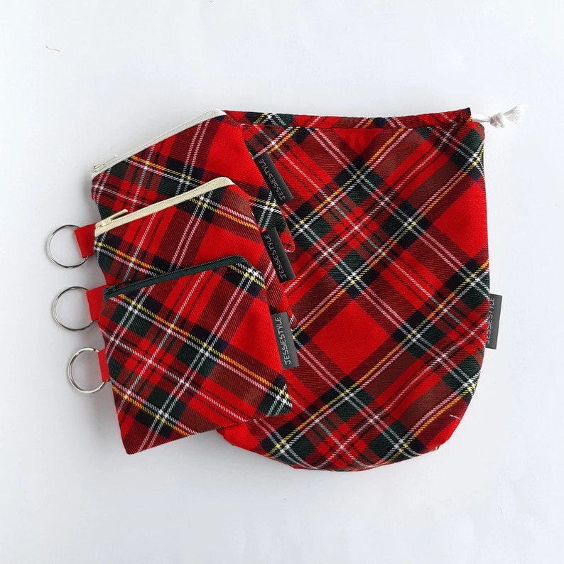 May include: Three red and black plaid zippered pouches with a drawstring bag. The pouches have a silver ring attached to the top. The bag and pouches have the text "JessStyle" printed on them.