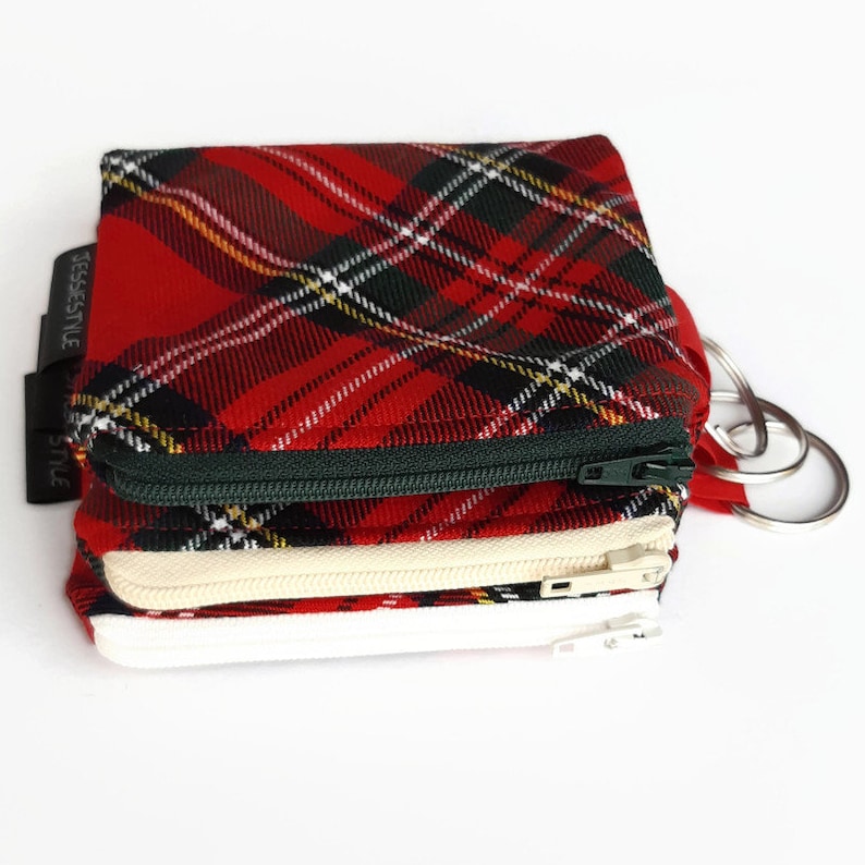 May include: Red, green, and white plaid zippered pouch with a key ring. The pouch has three compartments.