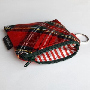 May include: Red and green plaid zippered pouch with a white and red striped lining. The pouch has a metal key ring attached.