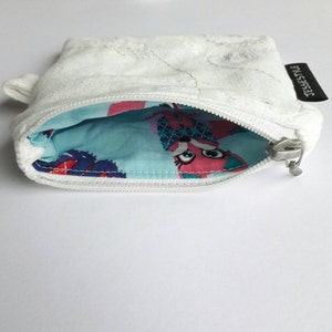 May include: White zippered pouch with a blue and pink patterned lining. The pouch has a small tag that says "JESSESTYLE".