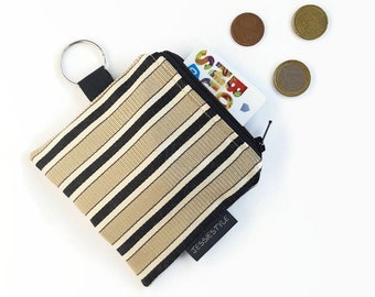 May include: A small beige and black striped zippered pouch with a key ring. The pouch has a black label that says "JessiesStyle".