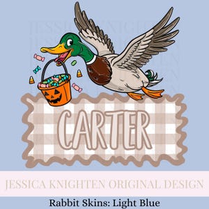 May include: A cartoon duck in flight, carrying a jack-o'-lantern bucket filled with candy. The duck has green, brown, and gray feathers. The name "CARTER" is displayed on a light brown plaid background. The design is set against a light blue backdrop.