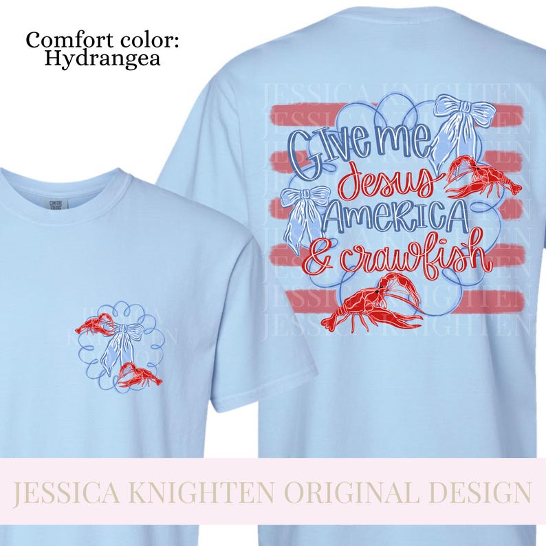Puede incluir: Camisetas de color azul claro con un dise&ntilde;o que incluye el texto "Give me Jesus America & crawfish". El dise&ntilde;o tambi&eacute;n presenta cangrejos rojos y lazos blancos. La camiseta es de color confort Hydrangea.