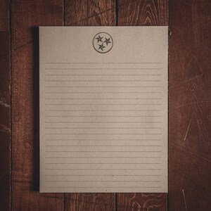 May include: A blank sheet of lined paper with a brown background. The paper has a circle with three stars in the center.