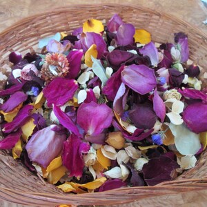 Puede incluir: Una cesta redonda de mimbre llena de p&eacute;talos de flores secas. Los p&eacute;talos son de color p&uacute;rpura, amarillo y blanco. La cesta est&aacute; hecha de material tejido de color marr&oacute;n claro.