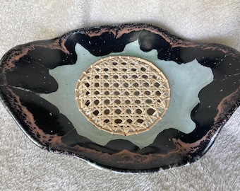 Black and gray ceramic compote with woven cane bottom. 8x7x3 inches