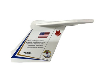 May include: White aircraft tail fin with a red, white and blue American flag, a red wolf logo, and the text "Thank you for your service advancing National interests by delivering diplomacy...safe, comfortable and reliable. "Perfection is our standard!" 70404"