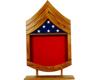 May include: Wooden flag display case with a red felt interior and a blue and white American flag with five stars on the top. The case is shaped like a chevron and has a stand.