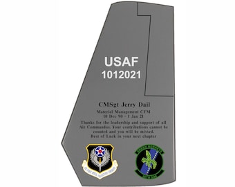 May include: A grey metal plaque with the text "USAF 1012021 CMSgt Jerry Dail Materiel Management CFM 10 Dec 90 - 1 Jan 21 Thanks for the leadership and support of all Air Commandos. Your contributions cannot be counted and you will be missed. Best of Luck in your next chapter" and two patches, one with the text "Air Force Special Operations Command" and the other with the text "Green Hornets 20th SOS".