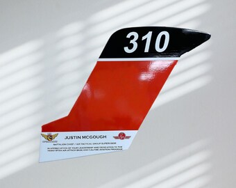 May include: A red and black plaque with the number 310 in white. The plaque features text that reads "JUSTIN MCGOUGH, BATTALION CHIEF/AIR TACTICAL GROUP SUPERVISOR" and "IN APPRECIATION OF YOUR LEADERSHIP AND DEDICATION TO THE HEMET/RYAN AIR ATTACK BASE AND CALFIRE AVIATION PROGRAM."