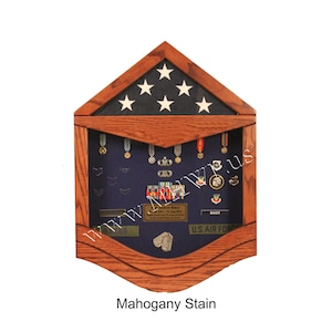 May include: A mahogany stained wooden shadow box with a blue felt background. The shadow box features a folded American flag with seven white stars, a nameplate, and a variety of military medals and ribbons.