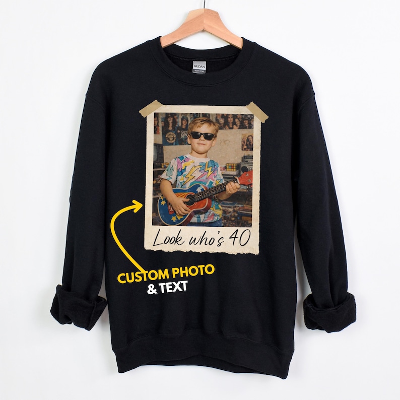 Puede incluir: Sudadera negra con foto y texto personalizados. La foto muestra a una persona con gafas de sol tocando la guitarra. El texto de la foto dice "Look who's 40". La sudadera tambi&eacute;n tiene el texto "CUSTOM PHOTO & TEXT".