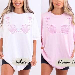 May include: White and blossom pink t-shirts with a seashell design in pink. The design includes the text "Jessica's Bachelorette" and "Miami May 2024". The shirts are short-sleeved and have a relaxed fit.