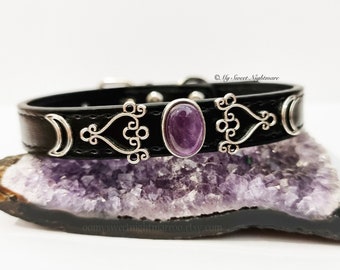 May include: Black leather dog collar with silver crescent moon and heart charms and a purple amethyst stone.