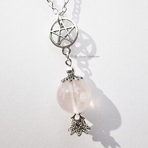Puede incluir: Un collar de cadena de plata con un dije de pentagrama y un dije de cuarzo rosa. El dije está rodeado de filigrana de plata.