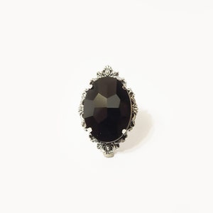 May include: A black gemstone ring with a silver ornate setting.