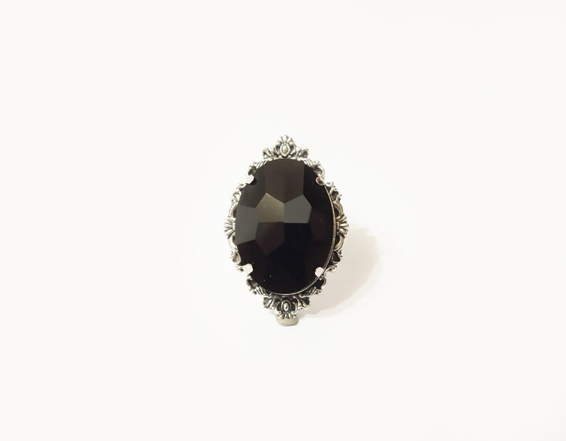 May include: A black gemstone ring with a silver ornate setting.