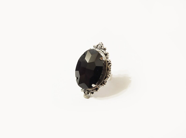 May include: A silver ring with a large, faceted black gemstone set in a decorative, ornate frame.