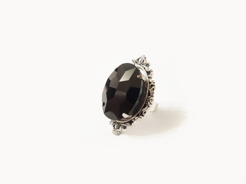 May include: A silver ring with a large, black, faceted gemstone set in a decorative, ornate frame.