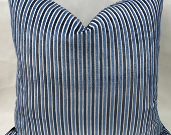 Puede incluir: Una funda de cojín de terciopelo a rayas azules y blancas. Las rayas son verticales y el cojín es rectangular.