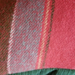 Puede incluir: Primer plano de una tela de cuadros rojos, verdes y azules. La tela tiene una textura suave y peluda.