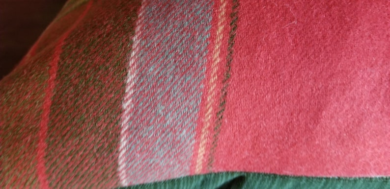 Puede incluir: Primer plano de una tela de cuadros rojos, verdes y azules. La tela tiene una textura suave y peluda.