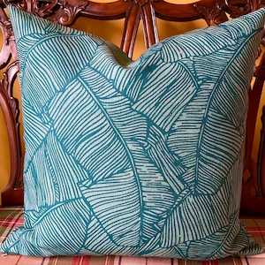 May include: Teal blue throw pillow with a white banana leaf pattern.