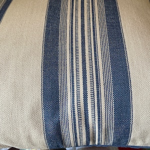 Puede incluir: Un primer plano de una almohada de rayas con rayas azules y blancas. La almohada est&aacute; hecha de una tela suave y texturizada.