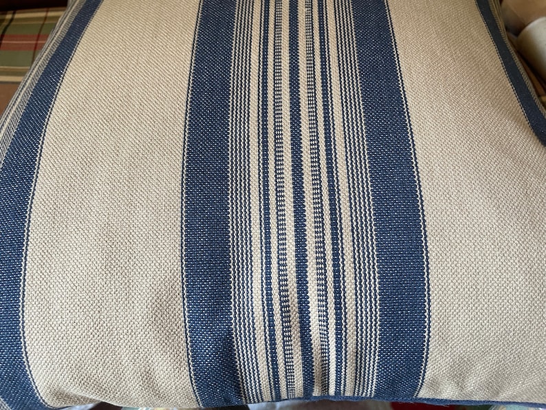Puede incluir: Un primer plano de una almohada de rayas con rayas azules y blancas. La almohada est&aacute; hecha de una tela suave y texturizada.