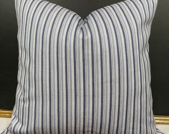 May include: A white and blue striped throw pillow with a subtle pattern of small dots. The pillow is made of a soft, woven fabric.