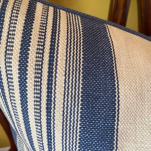 Puede incluir: Primer plano de una funda de coj&iacute;n a rayas azules y blancas. La tela tiene una textura tejida con peque&ntilde;os puntos blancos.