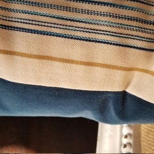 May include: A blue and white striped throw pillow with a gold stripe. The pillow is made of a soft, textured fabric.