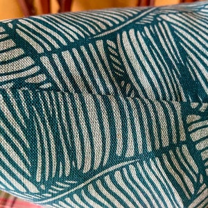 May include: Close-up of a teal and white striped fabric with a leaf pattern. The fabric has a textured weave.