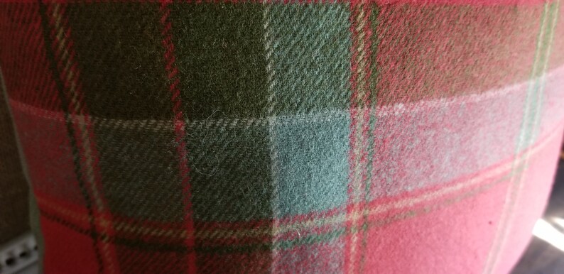Puede incluir: Primer plano de una tela de cuadros rojos, verdes y blancos. La tela tiene una textura suave y peluda.