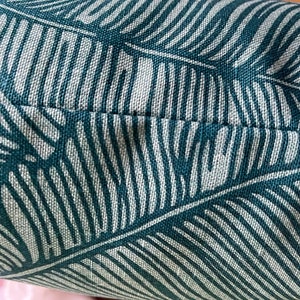 May include: Close-up of a teal and white patterned fabric with a subtle texture. The fabric features a repeating pattern of stylized leaves.