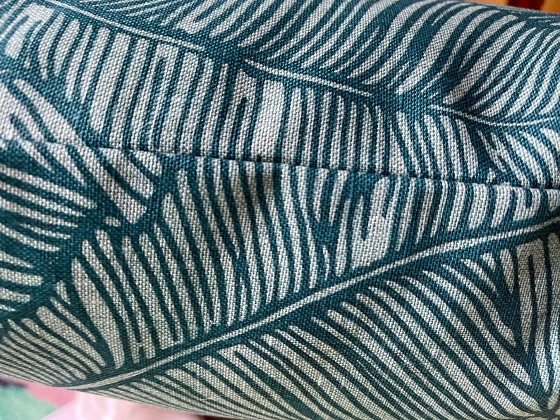 May include: Close-up of a teal and white patterned fabric with a subtle texture. The fabric features a repeating pattern of stylized leaves.