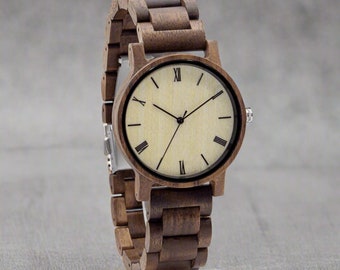 May include: A brown wooden wristwatch with a white face and black Roman numeral hour markers. The watch has a brown leather band.
