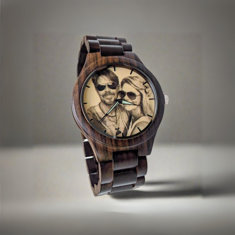 May include: A dark brown wooden wristwatch with a photo of a couple wearing sunglasses on the face.