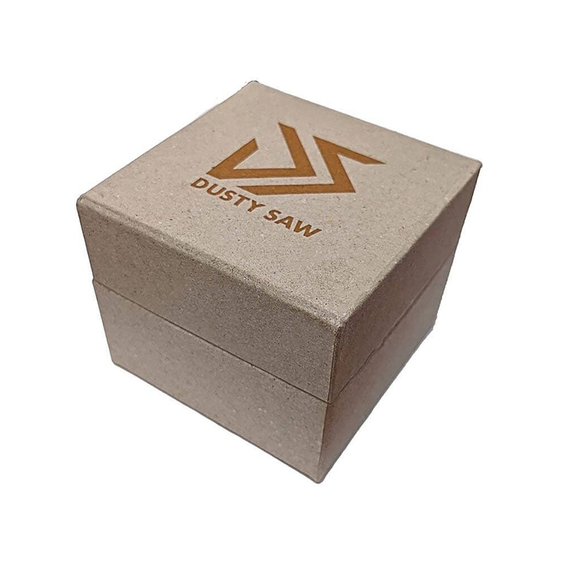 May include: A square, light brown cardboard box with a hinged lid. The top of the box features a geometric logo and the words "DUSTY SAW" printed in a darker brown. The box is closed and sits against a white background.