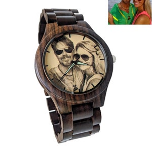 May include: A dark brown wooden wristwatch with a round face. The watch face displays a sepia-toned image of a couple wearing sunglasses. The watch strap is made of matching dark brown wood. A personalized gift.