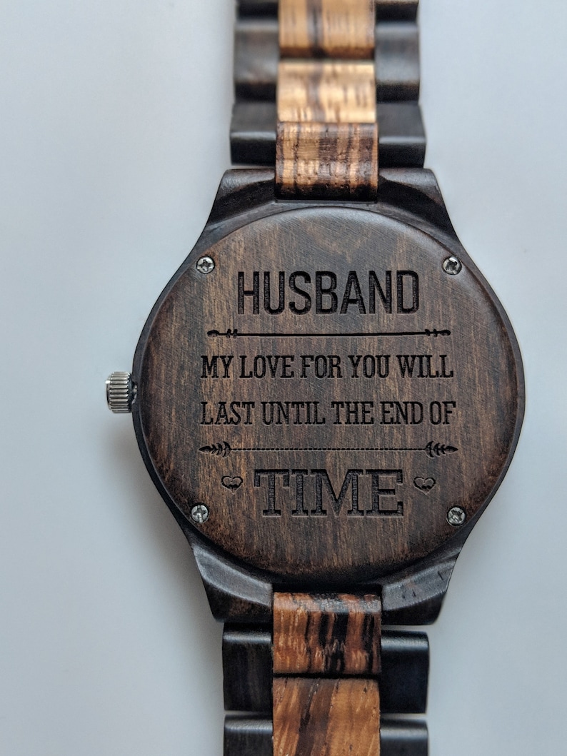 May include: A wooden wristwatch with a dark brown face and a matching wooden band. The watch face is engraved with the word "HUSBAND" above the inscription "MY LOVE FOR YOU WILL LAST UNTIL THE END OF TIME."