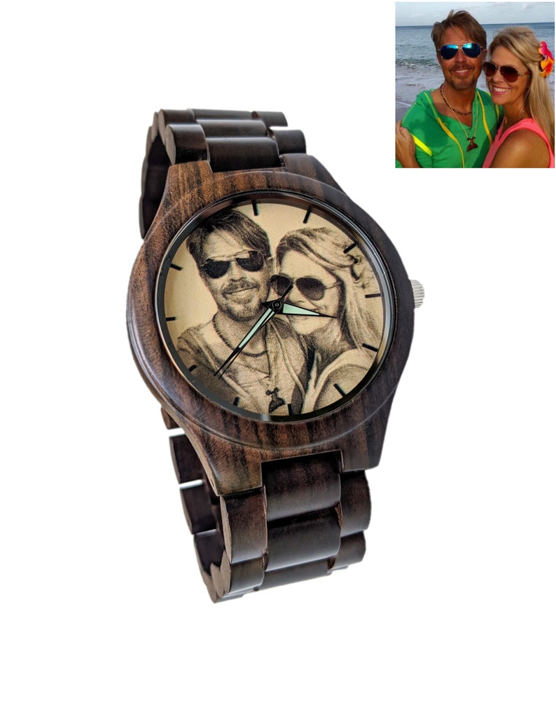 May include: Dark brown wooden wristwatch with a round face. The watch face features a black and white image of a couple wearing sunglasses. The watch band is made of matching dark brown wood. The watch has a silver crown.