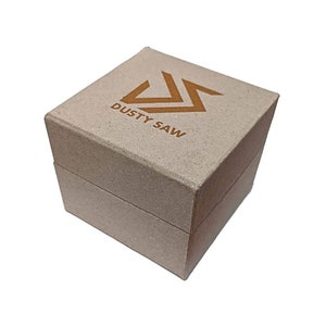 Pu&ograve; includere: Una scatola di cartone marrone con un logo che dice "DUSTY SAW" in lettere dorate. Il logo &egrave; una "S" stilizzata con una linea diagonale che la attraversa.