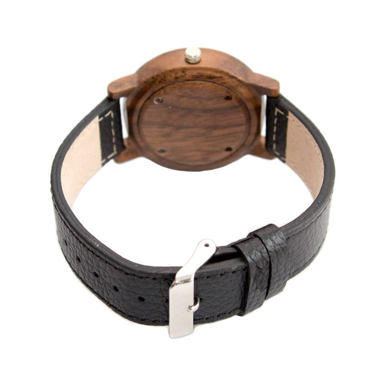 Pu&ograve; includere: Un orologio da polso in legno marrone con un cinturino in pelle nera e una fibbia argentata.